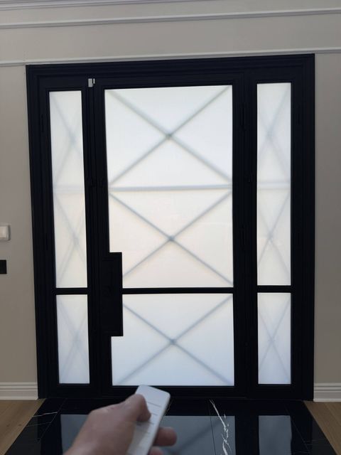 Real Smart View smart-film install in La Cañada Flintridge: a black-framed glass front door and sidelights switched to an even white frost for privacy, operated by a handheld remote