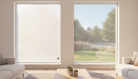Illustration of a bright living room with two matching street-facing picture windows fitted with switchable smart film, one frosted an even flat milky white and one clear with a handheld remote on the sill