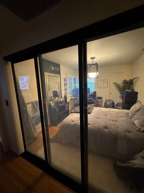 A Pasadena bedroom behind a steel-framed glass wall in the clear state, the bed and room visible through the glass