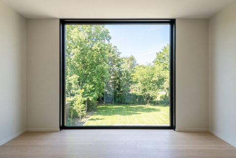 Black-framed smart glass picture window in clear mode, looking out to a green garden