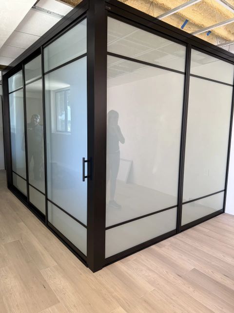 Real Smart View install: switchable glass room partitions in the frosted state, a flat even milky-white privacy wall around a glass-enclosed corner room