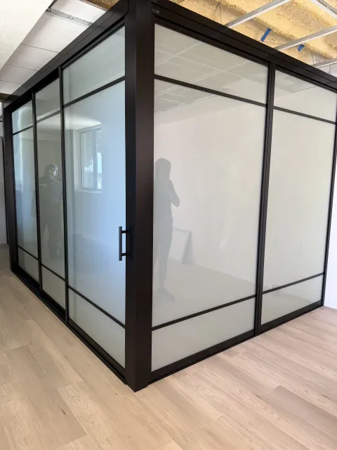The same switchable glass partitions seconds later in the frosted state, a flat even milky-white privacy wall on one switch