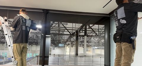 The Smart View crew on ladders applying switchable smart film onto a large glass partition
