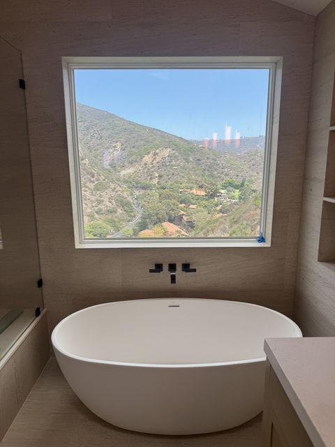 Smart film bathroom in Laguna Beach, the picture window over a freestanding tub clear with the canyon view beyond