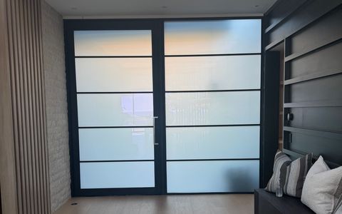 Smart film front door in Newport Beach frosted for privacy, black steel frame and side panel