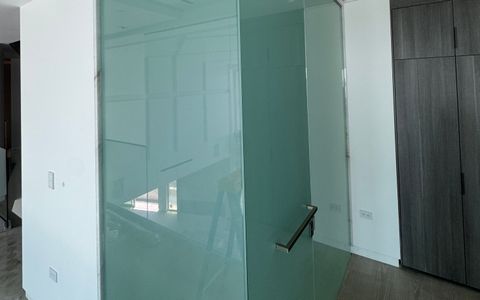Smart glass shower partition in Culver City switched to frosted, both faces of the glass corner an even milky white with the door handle in view