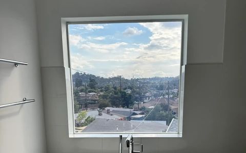 Smart glass bathroom window in Eagle Rock Los Angeles in clear mode with the hillside city view