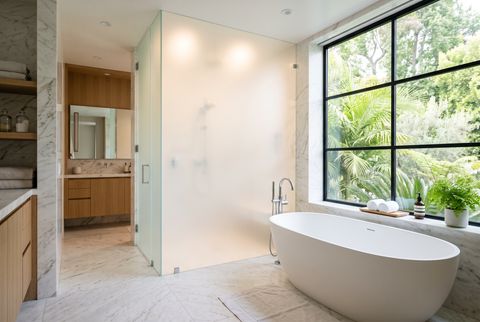Illustration: a bathroom drawn in two states — the window over the tub, the shower enclosure, and the WC partition shown clear on one side and switched to an even milky frosted privacy on the other