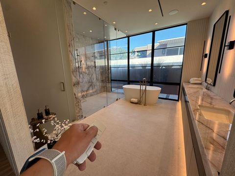 Hand holding the remote in the Newport Beach bathroom with the tub window clear