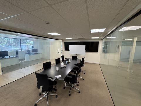 Corner boardroom in a Thousand Oaks office, frameless glass walls clear with smart film switched on