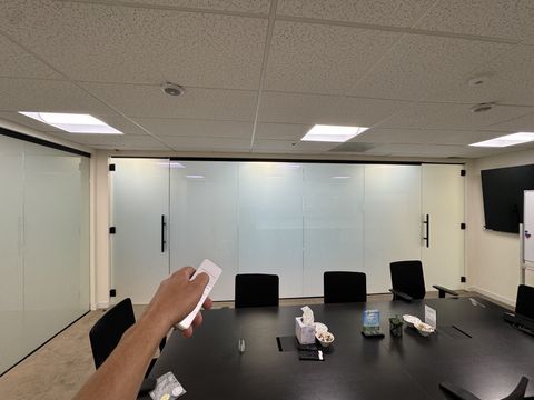 Hand holding the Smart View remote that frosts the conference room glass wall in a Thousand Oaks office