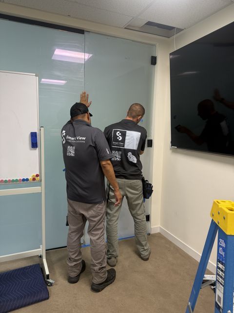 Smart View installers applying smart film to a glass conference room door in a Thousand Oaks office