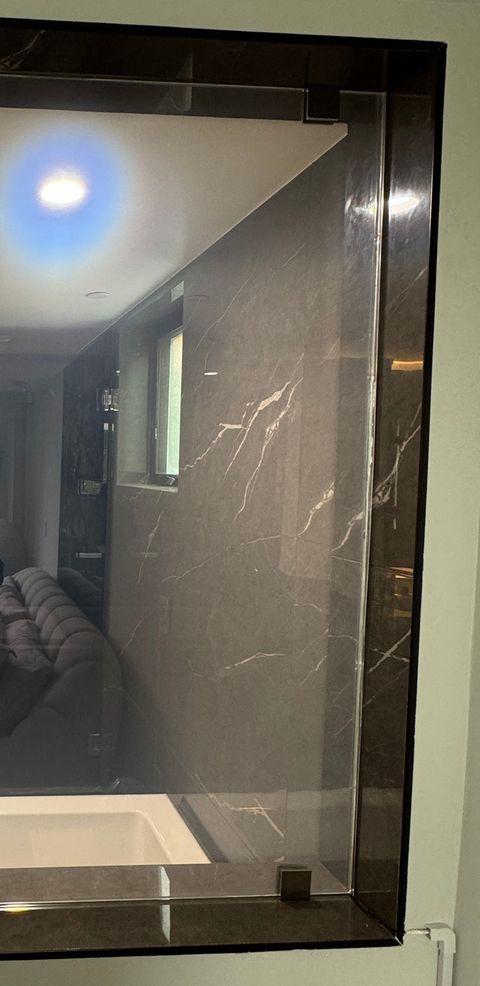 West Hollywood smart glass panel from the bedroom side, clear and looking through to the dark marble bathroom and tub