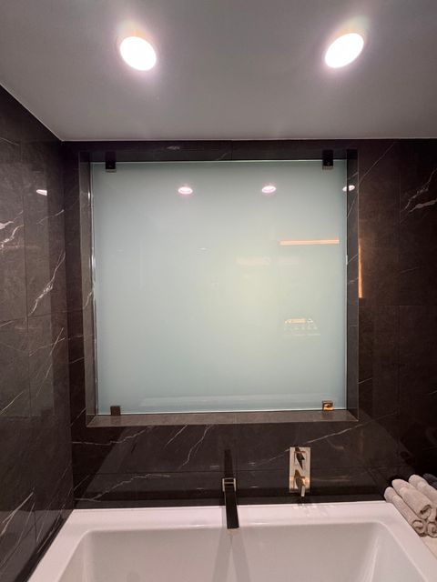 West Hollywood bathroom smart glass panel frosted to an even milky white above the marble tub deck