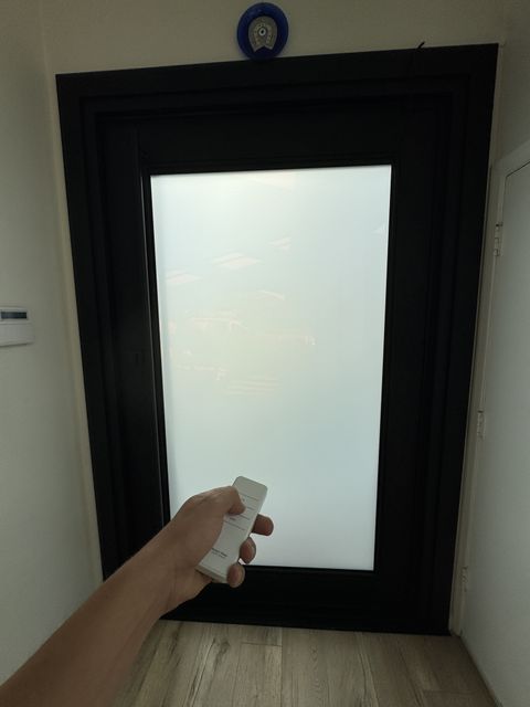 Hand holding the Smart View remote at the frosted Topanga front door