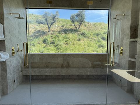 Smart glass shower wall in a marble bathroom, clear to a hillside view