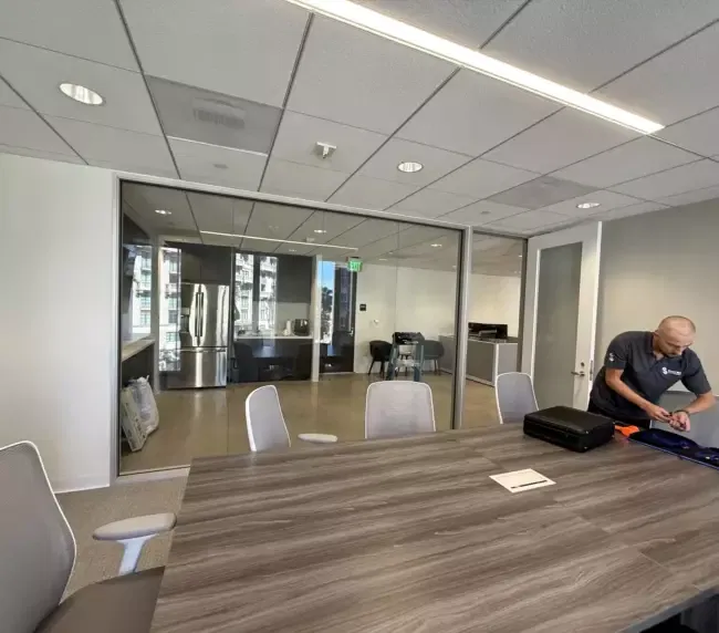 A technician from Smart View Film Solutions prepares to install switchable smart film on interior glass office walls in a modern Los Angeles conference room.