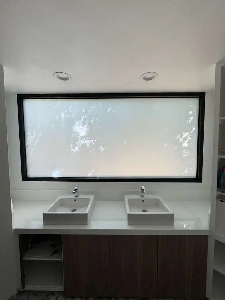 Smart glass bathroom window in Pasadena home switched to frosted privacy mode above double sinks