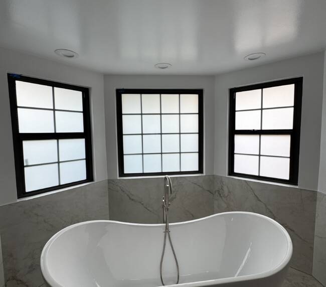 Smart glass West Covina CA bathroom windows in frosted privacy mode above a freestanding tub