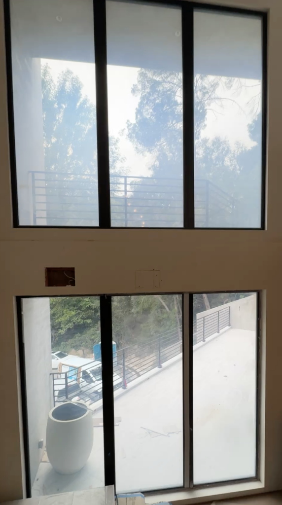 Side angle of a tall switchable glass window arrangement in a Hollywood Hills hillside home