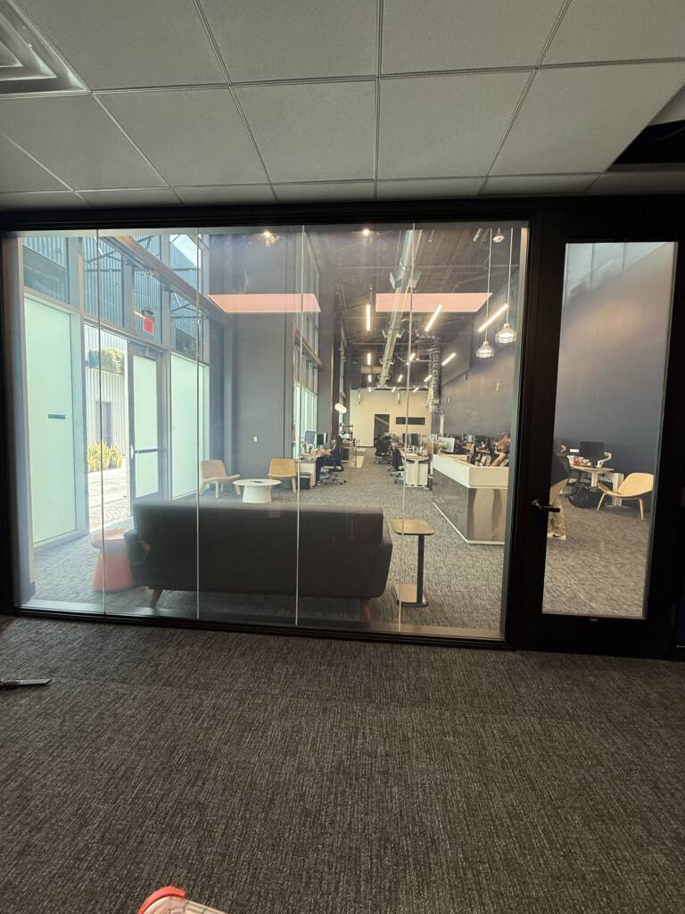 Smart glass LAX office Inglewood — multi-panel partition wall in frosted state separating lounge and office
